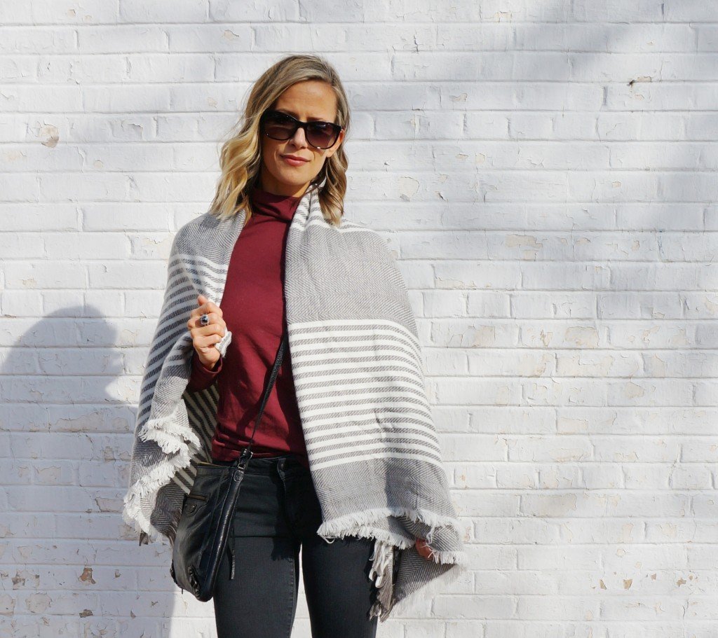 Thanksgiving outfit: burgundy turtleneck, poncho, black denim, boots, crossbody