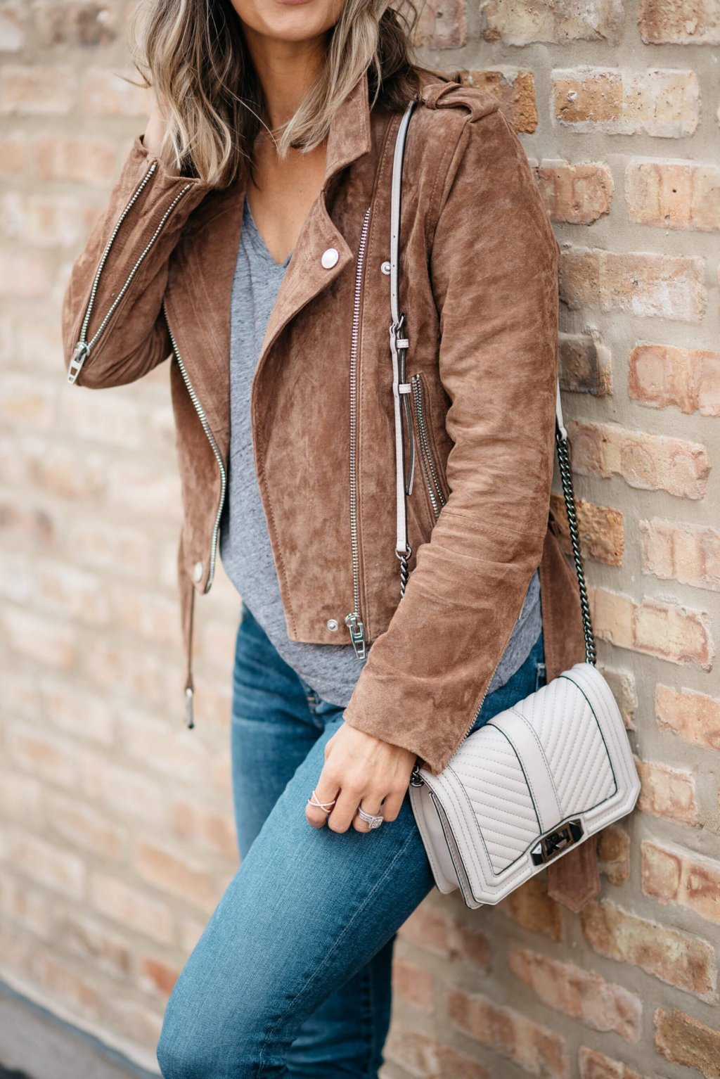 Grey tee, moto jacket, denim, sneakers, sunglasses, crossbody bag