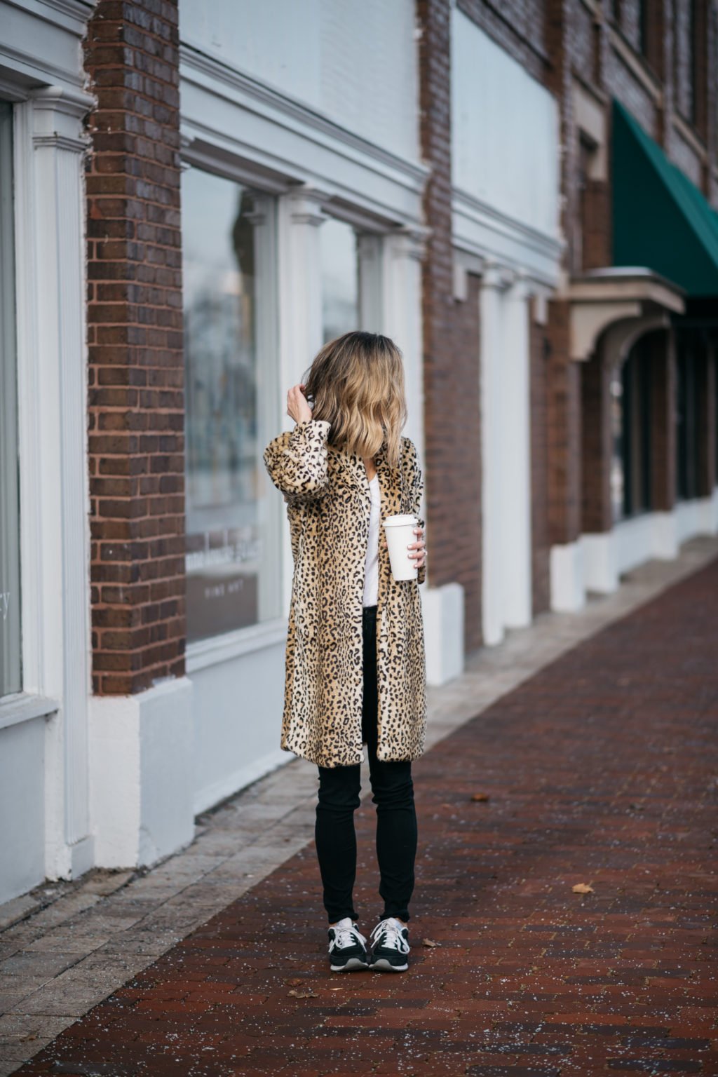 Leopard print coat, tee, black denim, sunglasses, and sneakers
