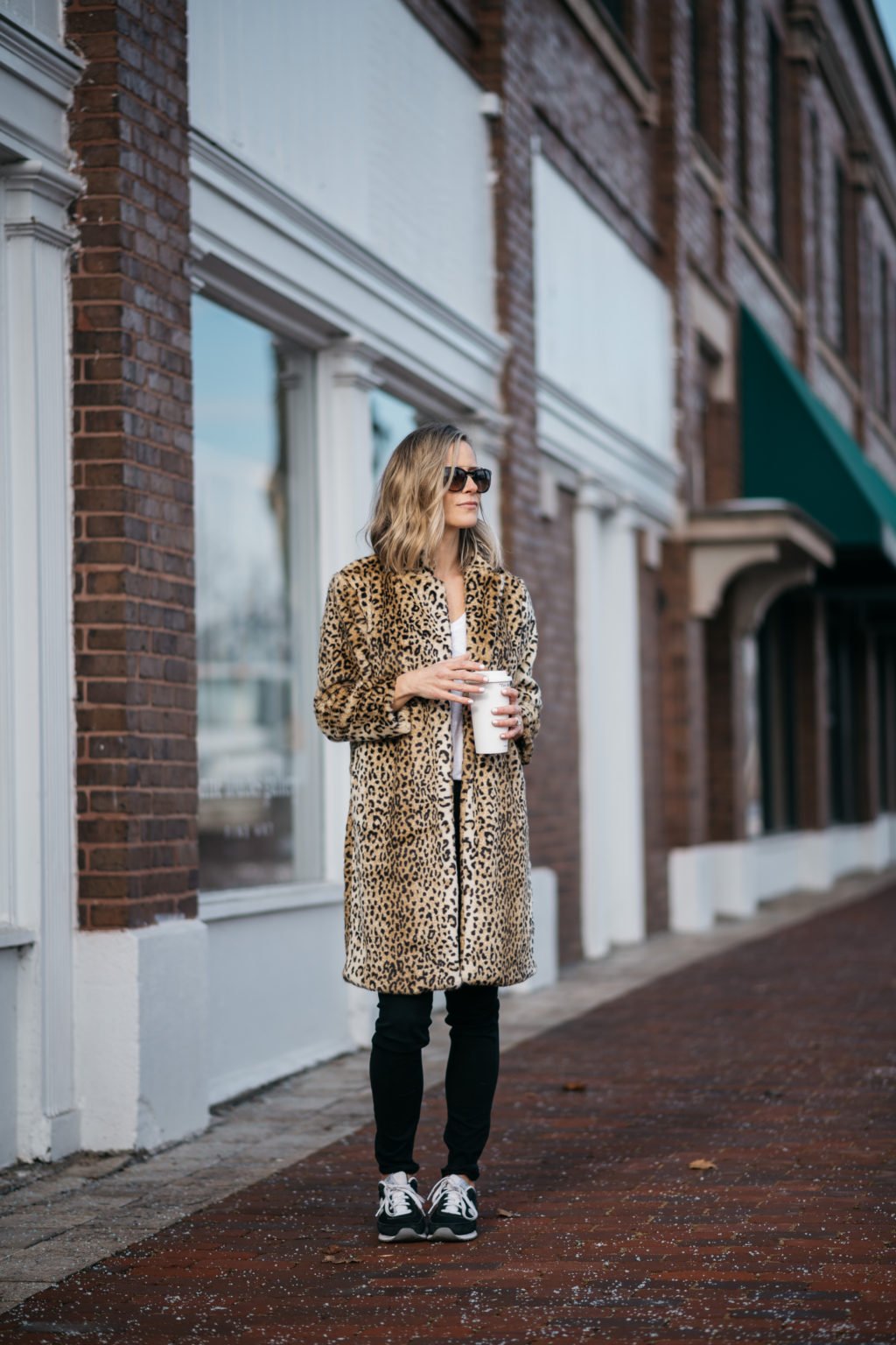 Leopard print coat, tee, black denim, sunglasses, and sneakers