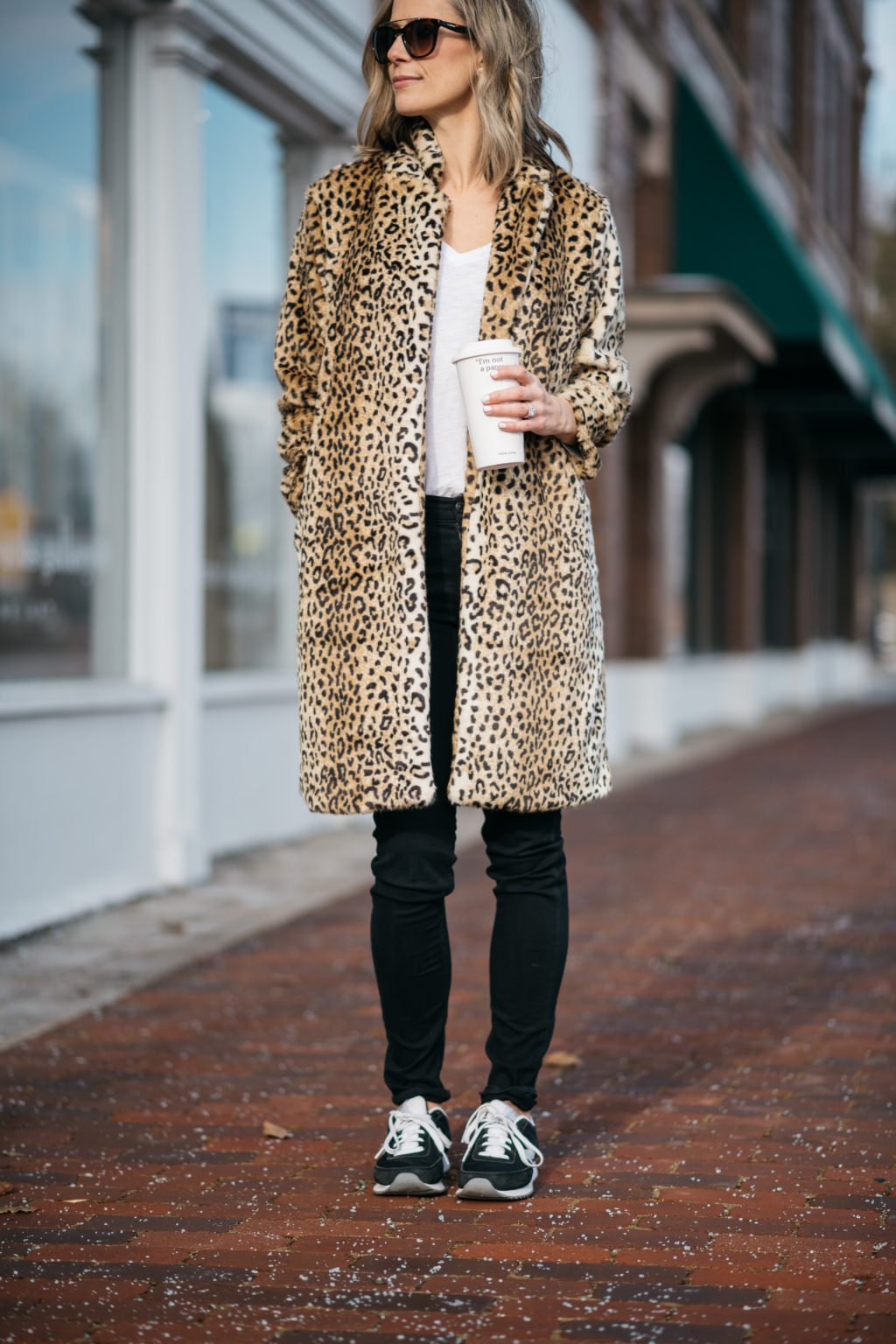 Leopard print coat, tee, black denim, sunglasses, and sneakers