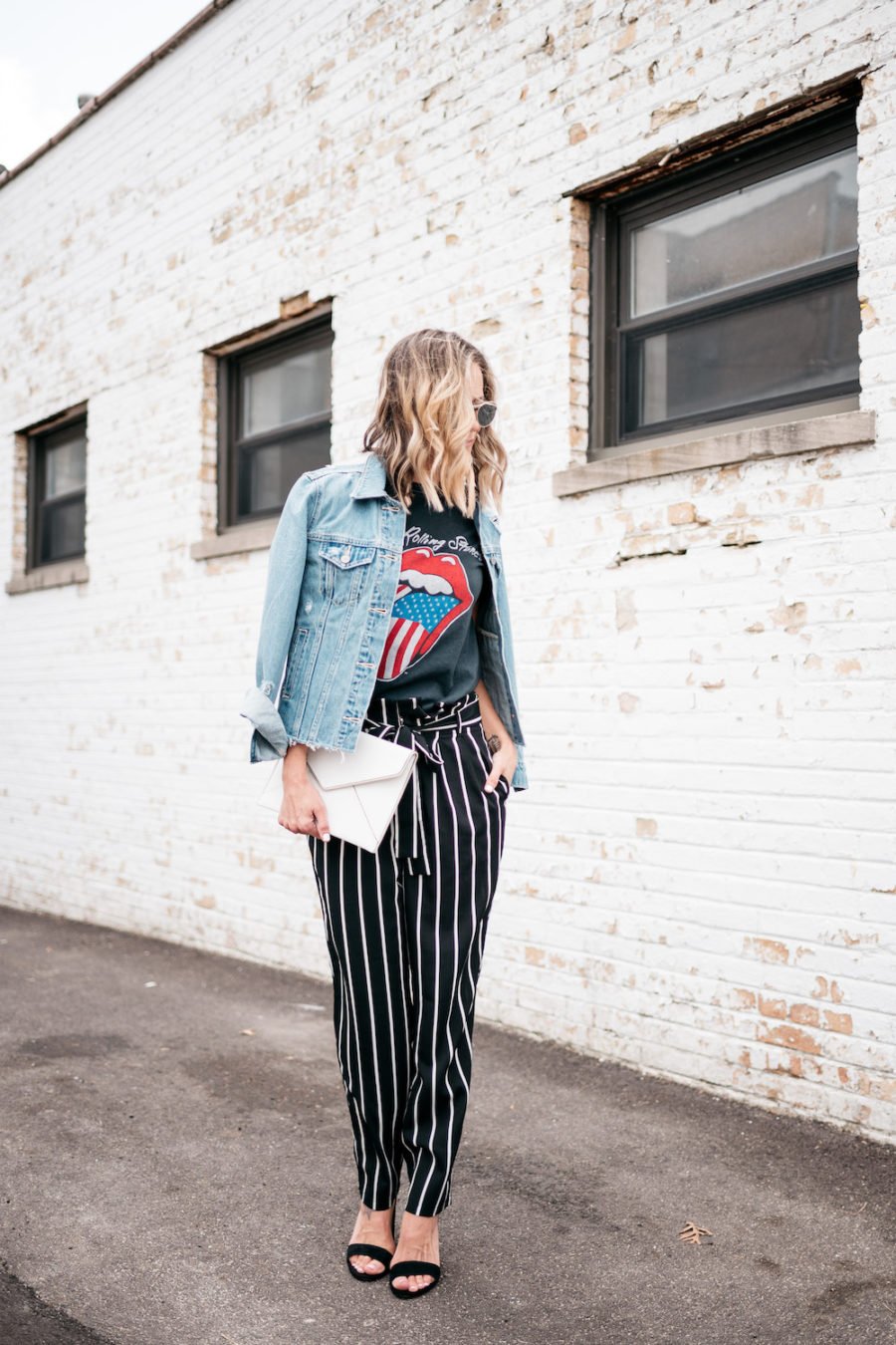 Band tee, striped pants, denim jacket, heels, clutch, sunglasses
