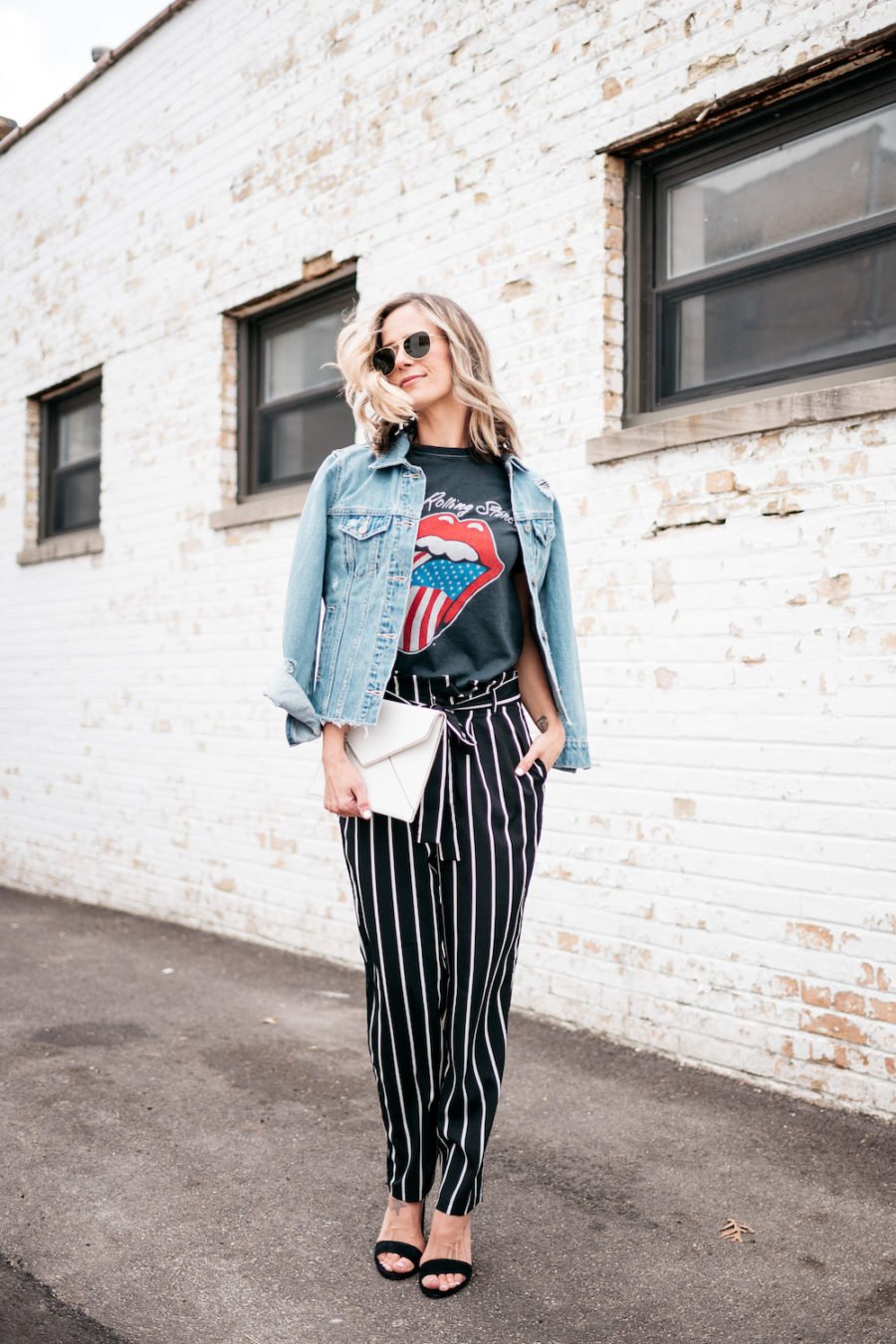 Band tee, striped pants, denim jacket, heels, clutch, sunglasses