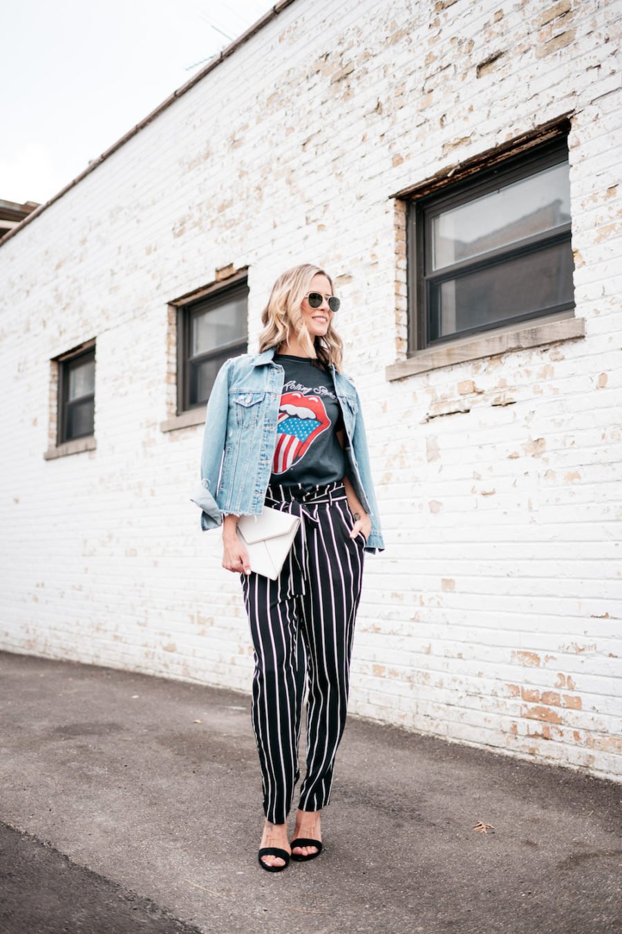 Band tee, striped pants, denim jacket, heels, clutch, sunglasses