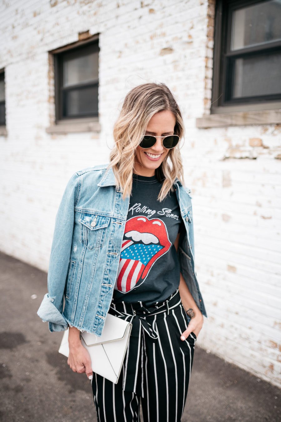 Band tee, striped pants, denim jacket, heels, clutch, sunglasses