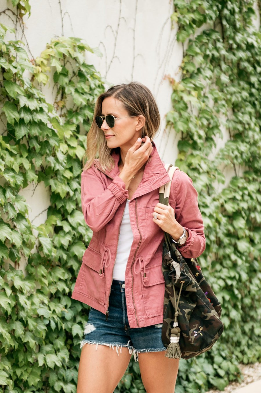 White tank, denim shorts, pink jacket, camo bag
