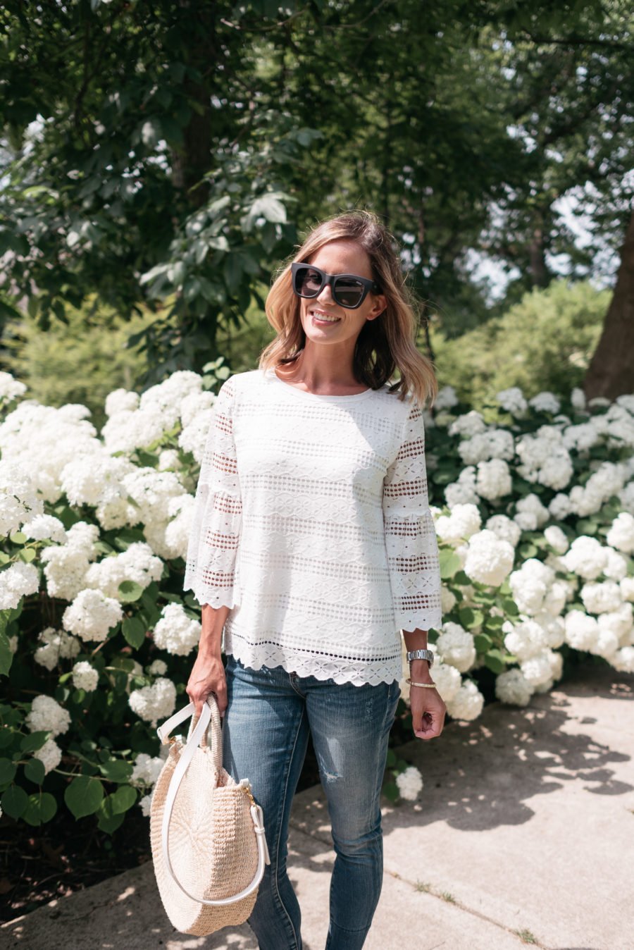 White bell sleeve top, sunglasses, straw bag