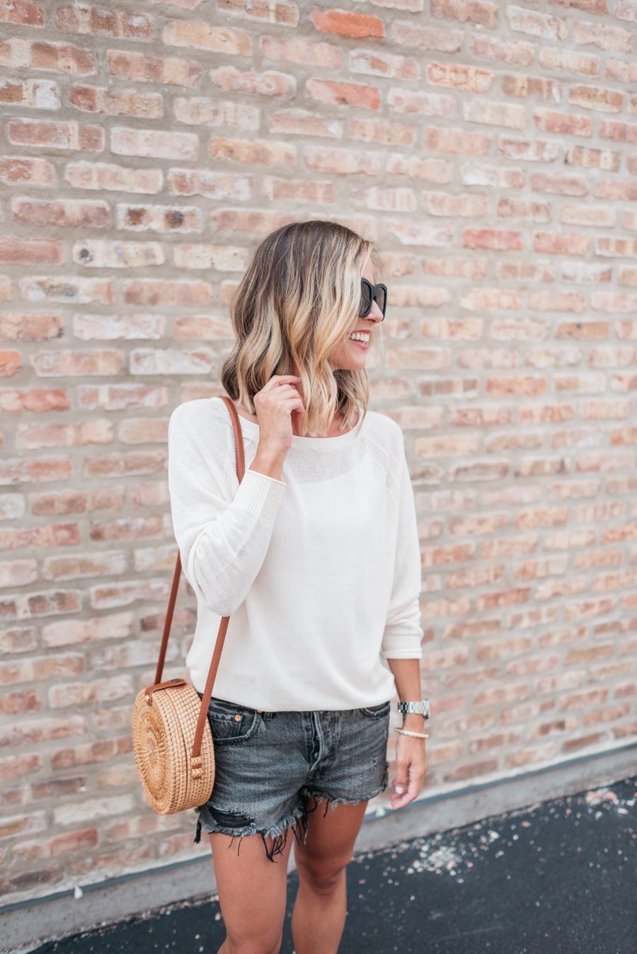 White long sleeve tee, black cut offs, sandals, straw bag, and sunnies
