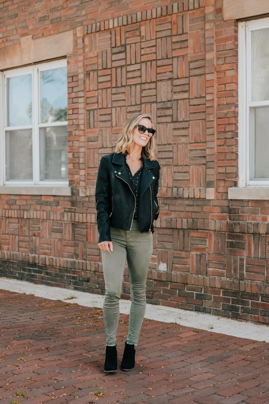 Budget friendly style: olive pants, polka dot blouse, moto jacket, booties, and sunglasses