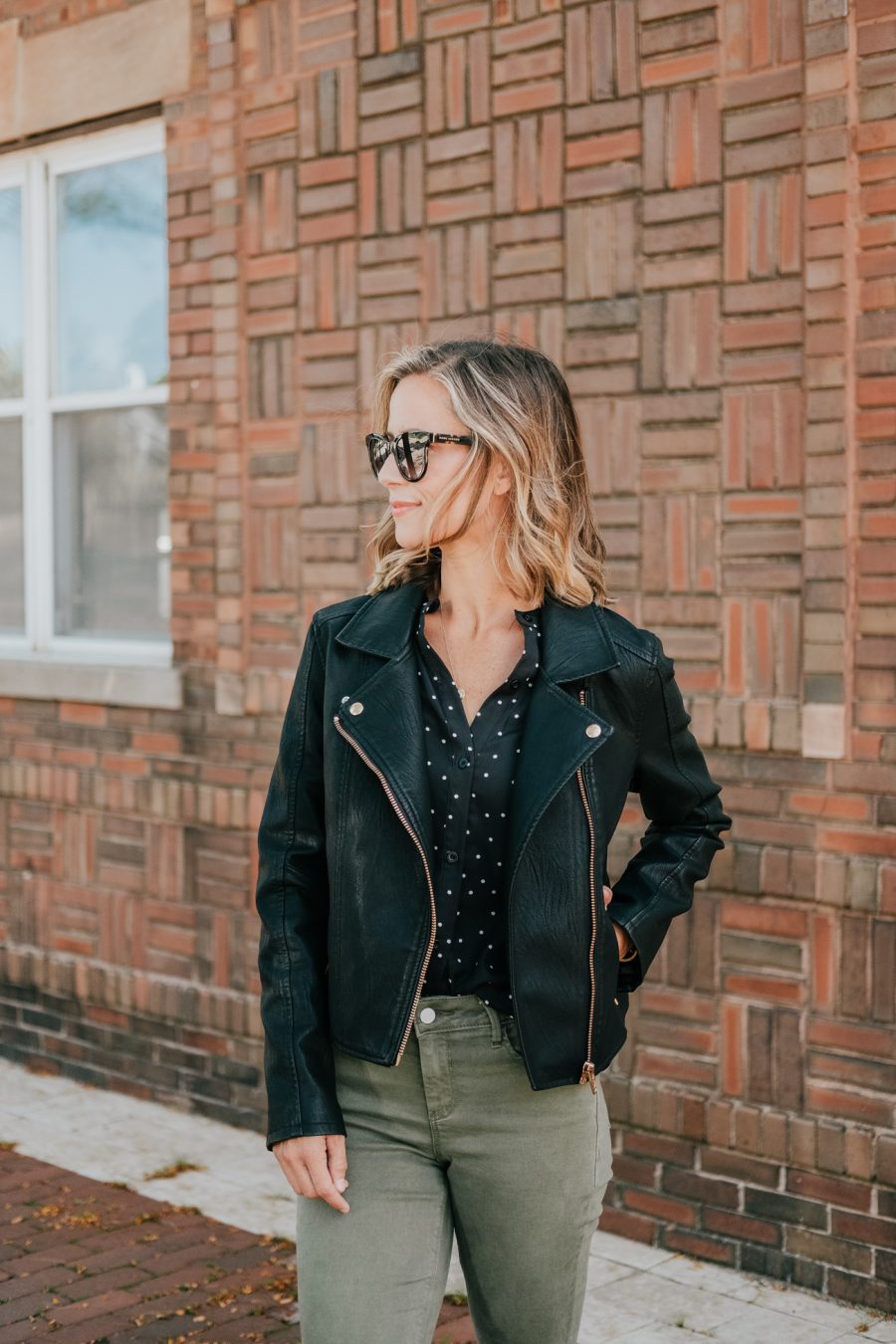 Budget friendly style: olive pants, polka dot blouse, moto jacket, booties, and sunglasses