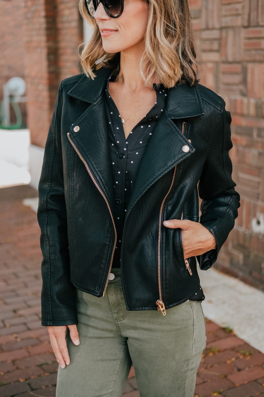 Budget friendly style: olive pants, polka dot blouse, moto jacket, and sunglasses
