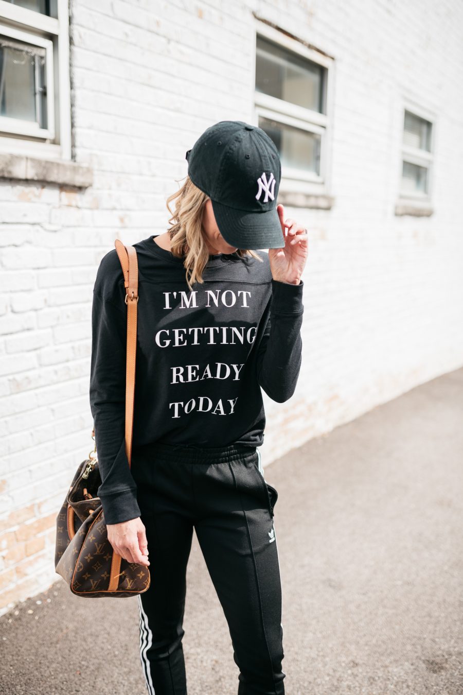 Pullover, Adidas track pants, Louis Vuitton bag, Nike hat