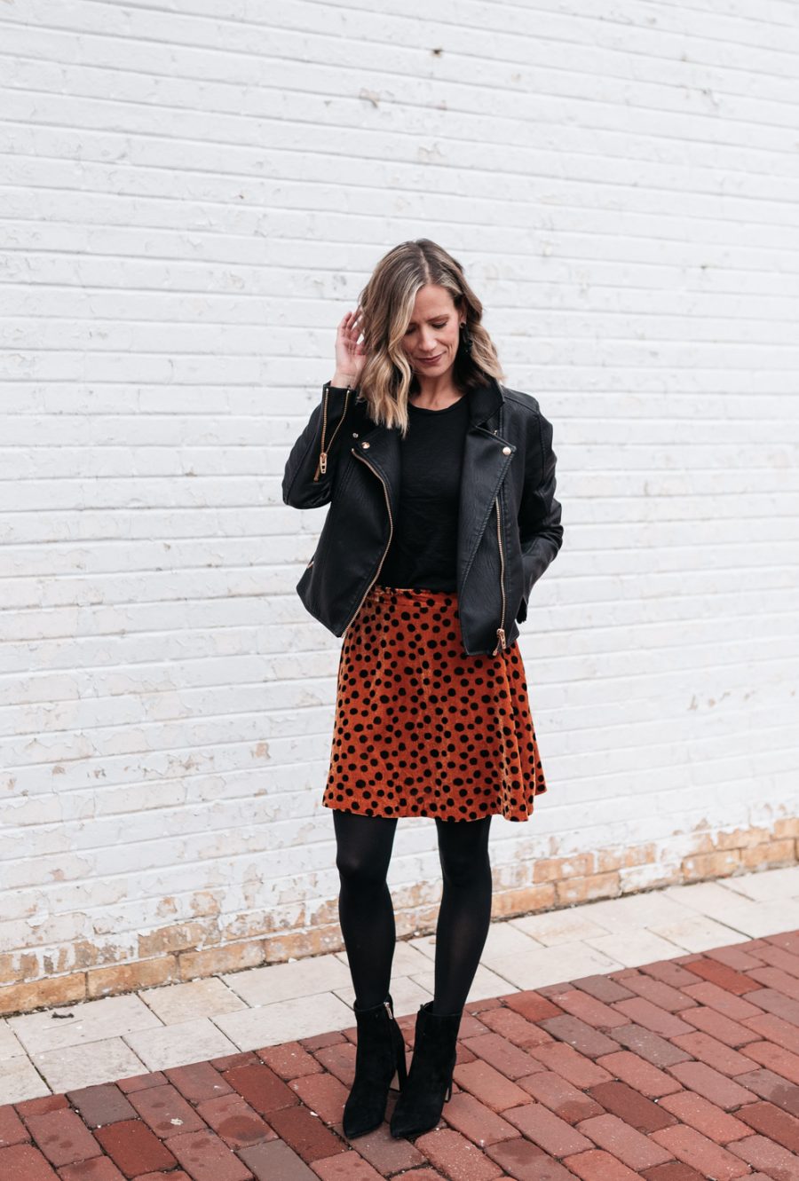 Cozy holiday party outfit: leopard skirt, tights, booties, and moto jacket