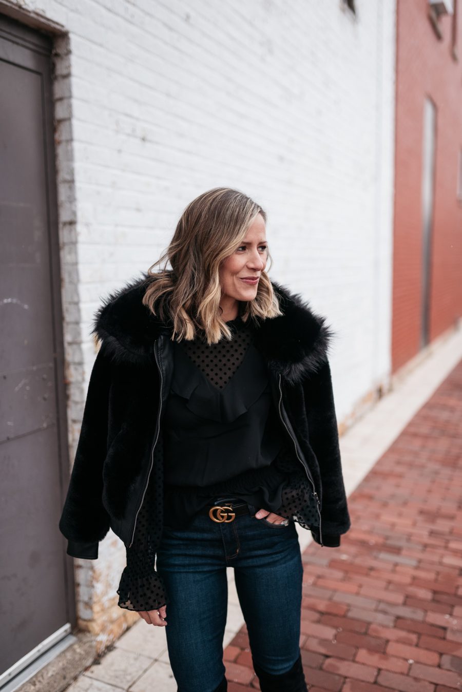 Faux fur jacket, black blouse, skinny jeans, and over the knee boots