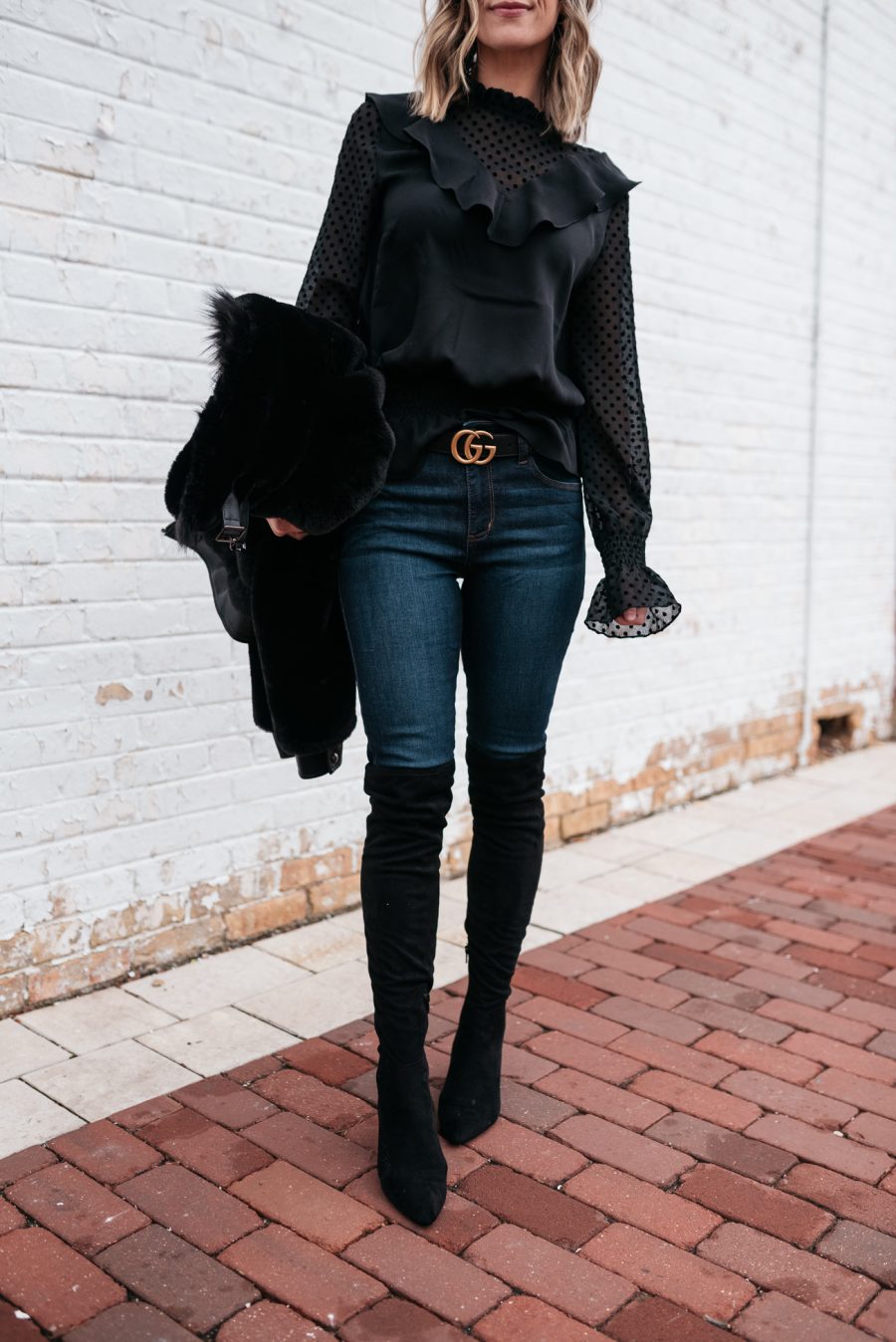 Faux fur jacket, black blouse, skinny jeans, and over the knee boots