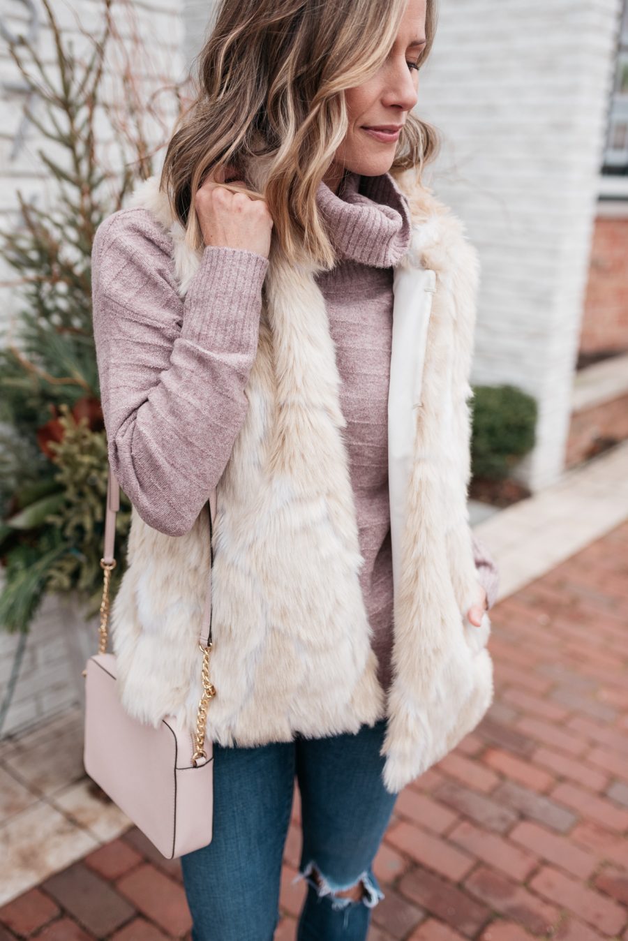 pink turtleneck, faux fur vest, skinny jeans, crossbody, and booties
