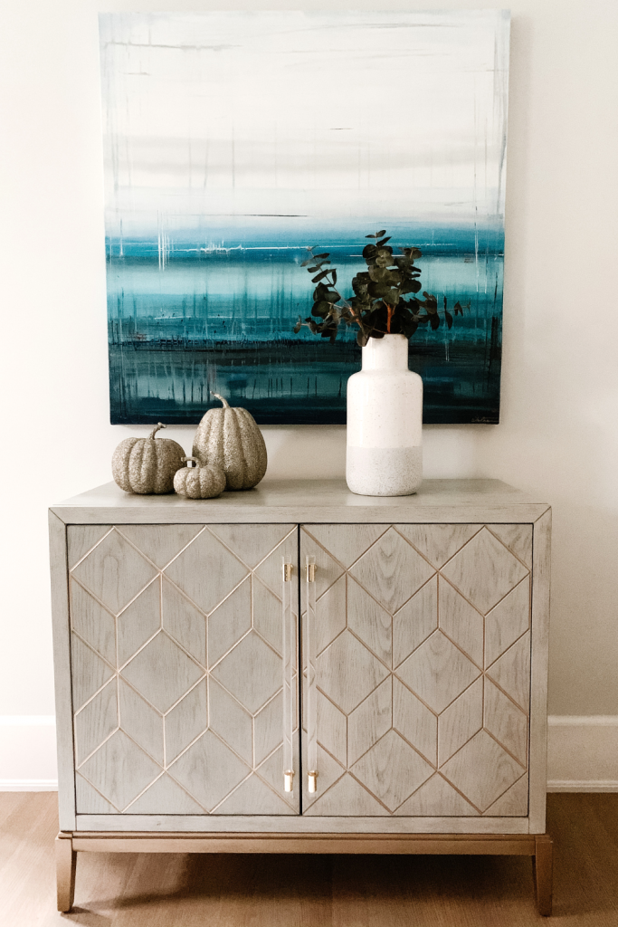 A warm and welcoming dining room of neutrals, comfortable seating, and beautiful accent lighting and art