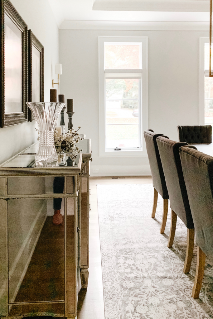 A warm and welcoming dining room of neutrals, comfortable seating, and beautiful accent lighting and art