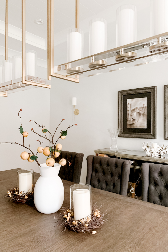 A warm and welcoming dining room of neutrals, comfortable seating, and beautiful accent lighting and art