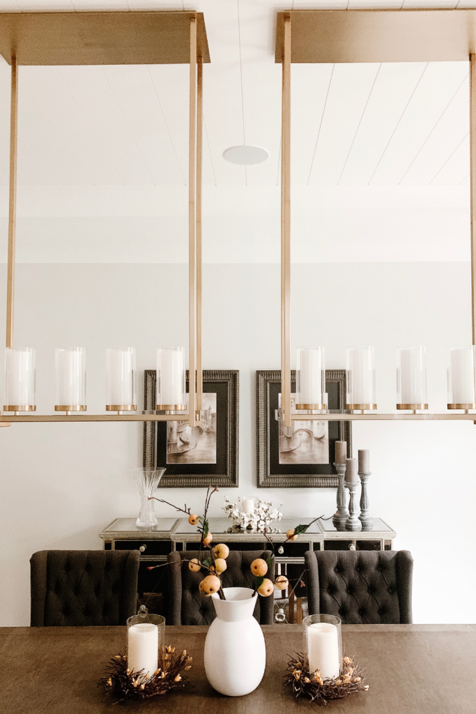 A warm and welcoming dining room of neutrals, comfortable seating, and beautiful accent lighting and art