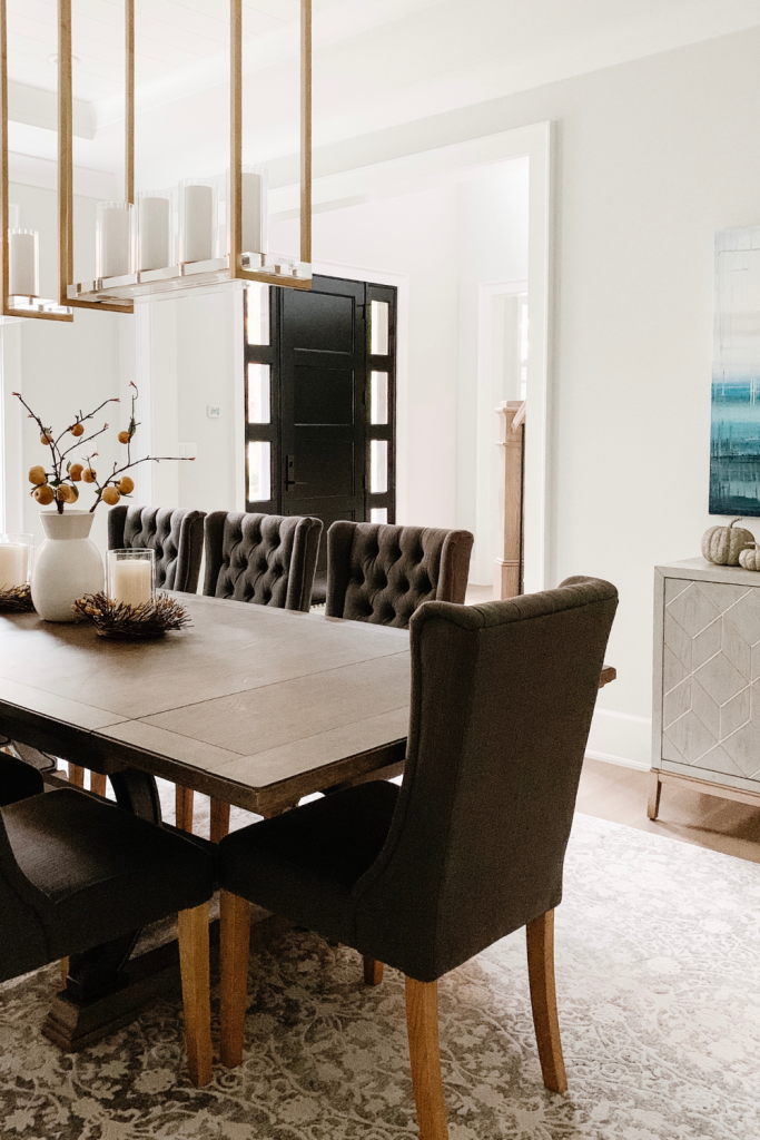 A warm and welcoming dining room of neutrals, comfortable seating, and beautiful accent lighting and art