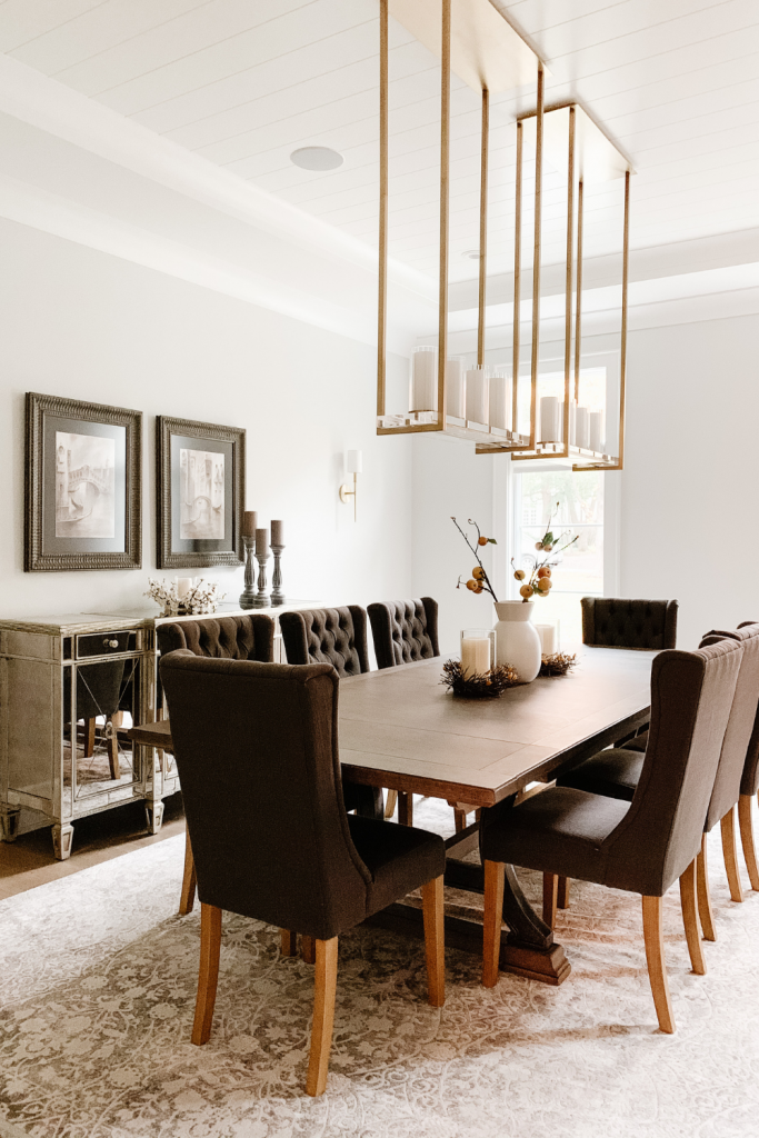 A warm and welcoming dining room of neutrals, comfortable seating, and beautiful accent lighting and art
