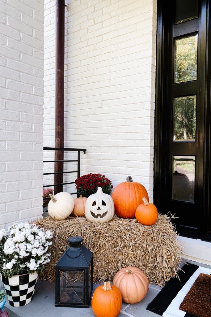 We gave our front porch a fall makeover complete with a freshly painted black door, pumpkins, mums, and a hay bail.