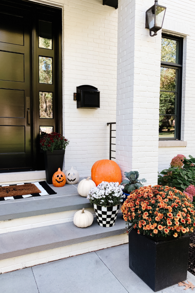 We gave our front porch a fall makeover complete with a freshly painted black door, pumpkins, mums, and a hay bail.