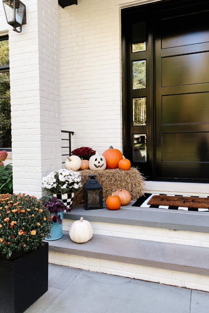 We gave our front porch a fall makeover complete with a freshly painted black door, pumpkins, mums, and a hay bail.