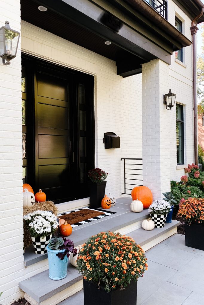 We gave our front porch a fall makeover complete with a freshly painted black door, pumpkins, mums, and a hay bail.