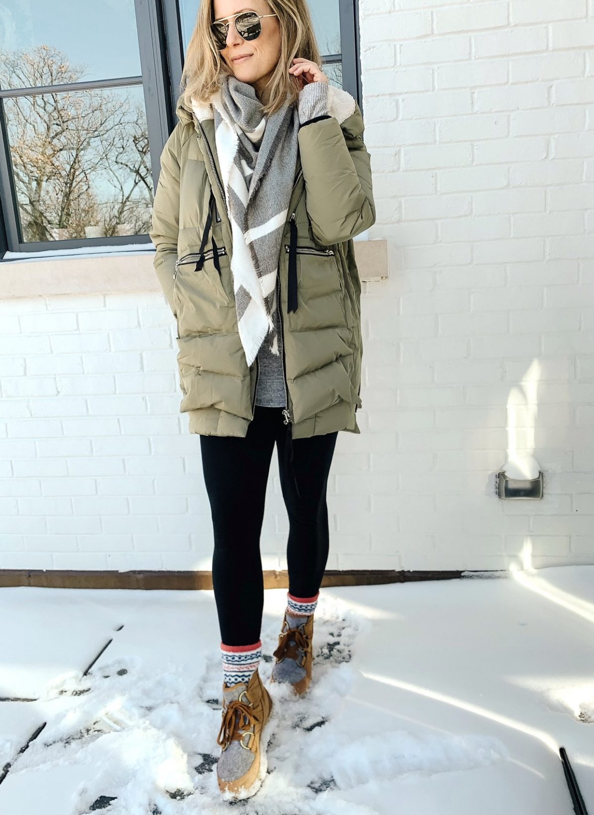 Suzanne in the snow wearing an Amazon coat, leggings, and boots