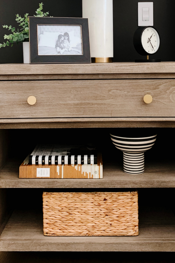 How to style a nightstand: lamp, table clock, framed pictured, basket, and books