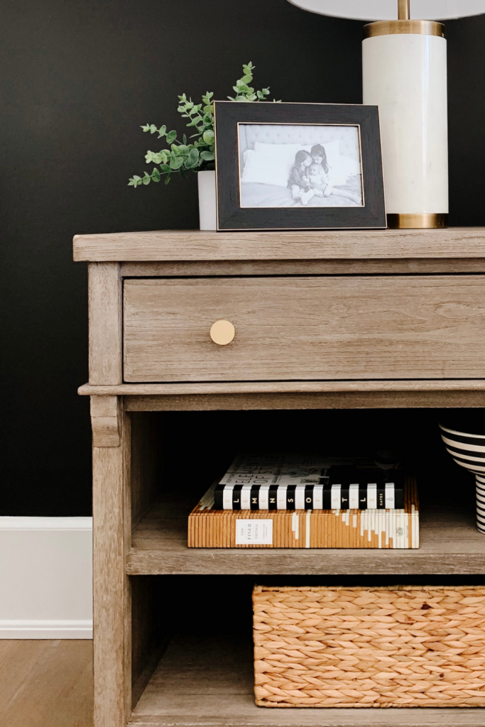 How to style a nightstand: lamp, table clock, framed pictured, basket, and books