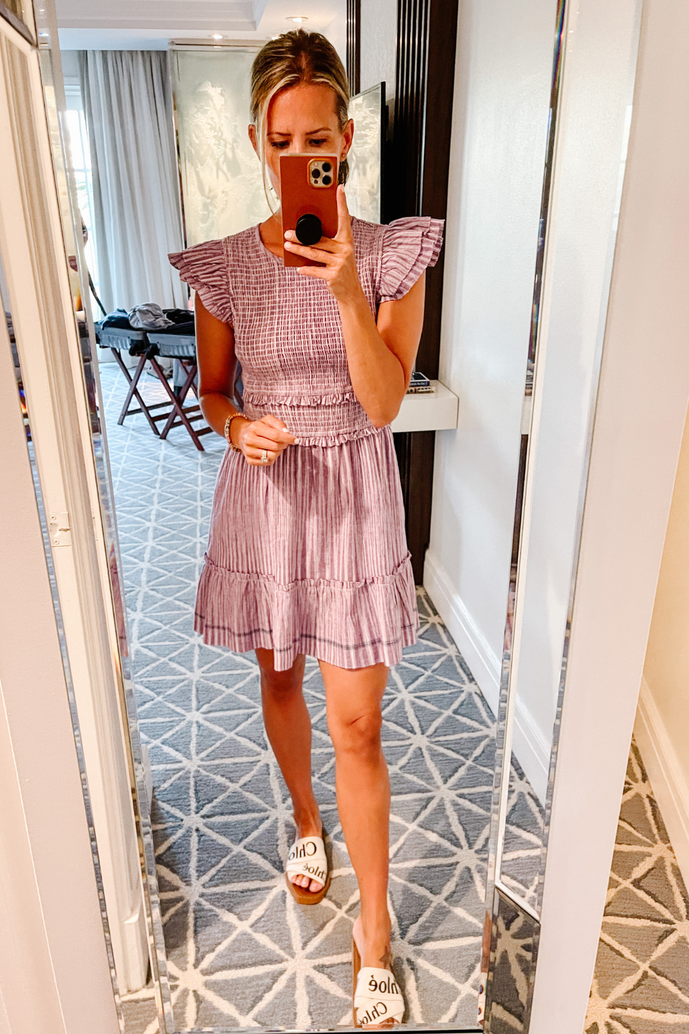 Suzanne wearing a striped mini dress and Chloe slides