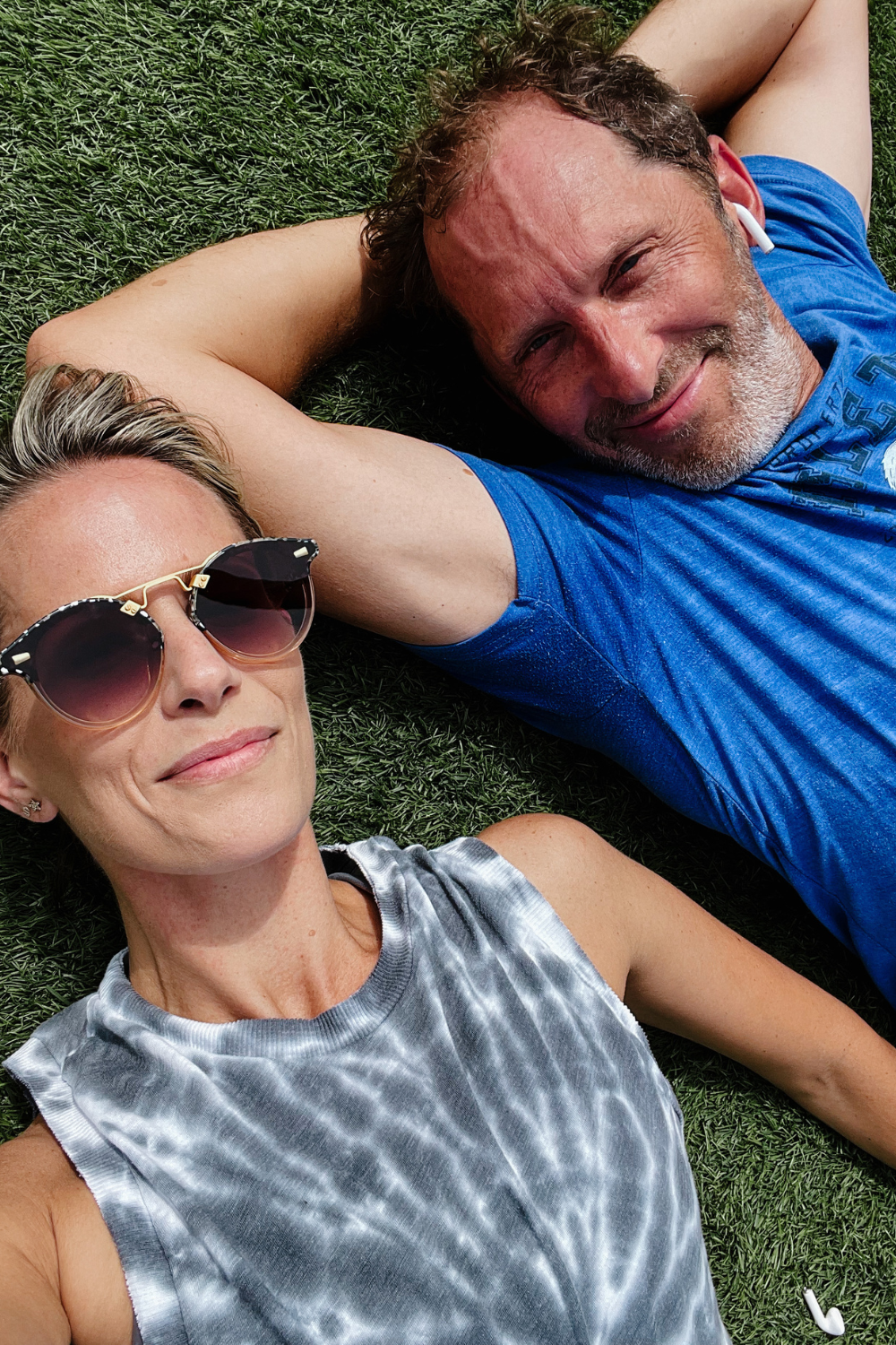 Suzanne and The Mister laying on the grass after a workout