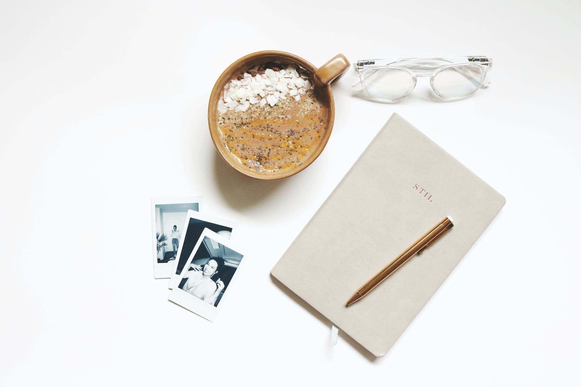 brown ceramic cup beside notebook and pen