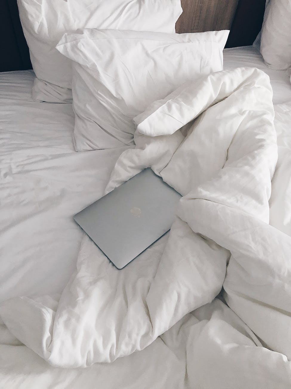 laptop on unmade bed in morning